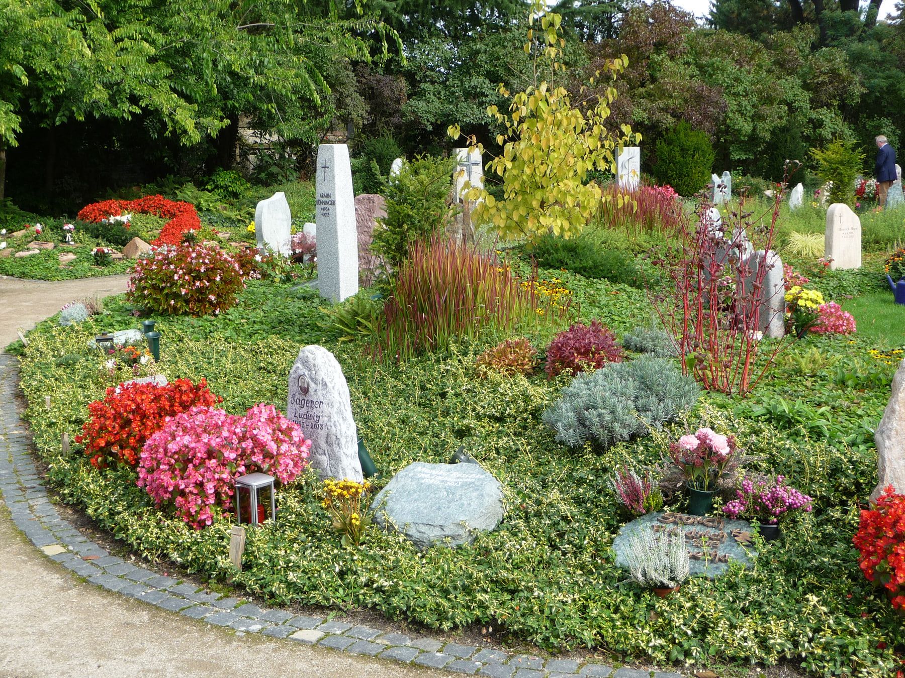 Farbenreich bepflanztes Grabfeld mit niedrigen individuellen Grabsteinen auf Hauptfriedhof Mannheim